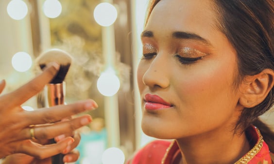 makeup artist applying makeup with brush to a woman